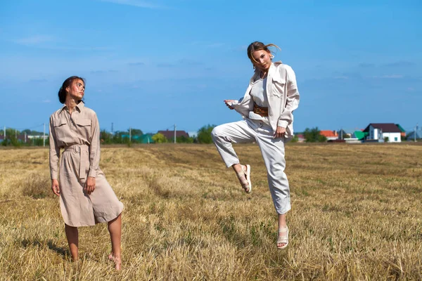 两个穿着米色西服的漂亮模特儿站在割地里麦子的背景上 — 图库照片
