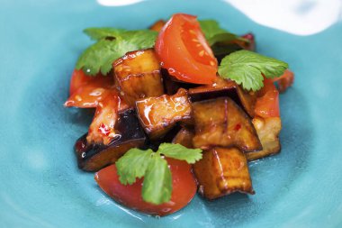 Mavi tabakta soslu kızarmış patlıcan ve domates salatası