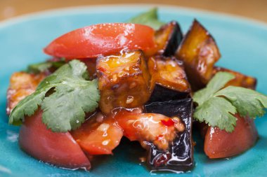 Mavi tabakta soslu kızarmış patlıcan ve domates salatası