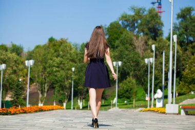 Mavi elbiseli, yaz caddesinde yürüyen neşeli bir kızın tam boy portresi.