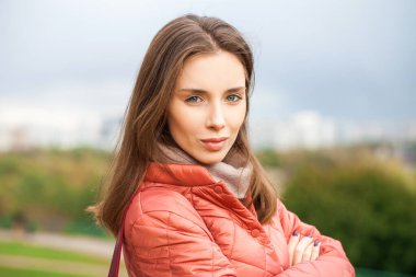 Mercan ceketli güzel esmer bir mankenin yakın portresi.