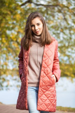 Mercan ceketli güzel esmer bir mankenin yakın portresi.