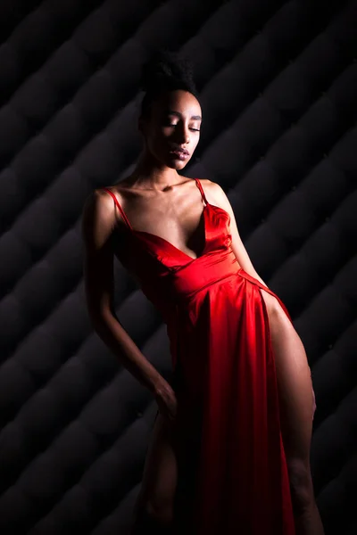 赤いドレスの官能的な若いアフリカ女性の肖像画を閉じます 暗い壁の背景に女性のスタジオ撮影 — ストック写真