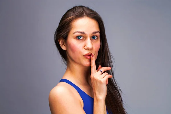 女性には 沈黙が必要です 若い美しいブルネットのモデルは 灰色の背景に分離された沈黙の記号として唇に人差し指を入れています — ストック写真
