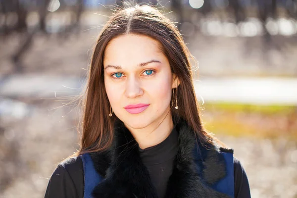 春天公园里一位穿着蓝色外套的年轻美女的肖像 — 图库照片