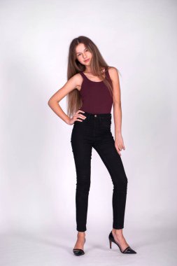 Beyaz arka planda izole edilmiş siyah kotlu güzel sarışın bir mankenin tam vücut portresi.