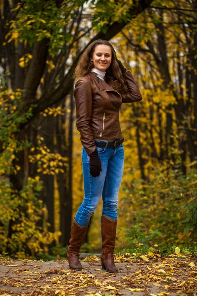 Full body portrait of a young beautiful girl in blue jeans in autumn park
