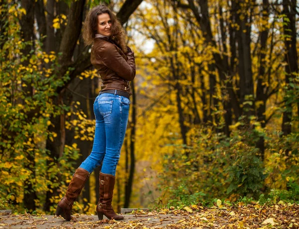 秋天公园里一个穿着蓝色牛仔裤的年轻漂亮姑娘的全身像 — 图库照片