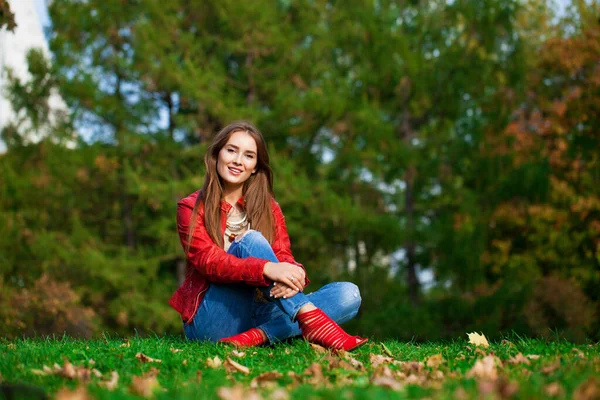 Güz Parkında Oturan Kırmızı Deri Ceketli Mavi Kotlu Güzel Bir — Stok fotoğraf