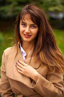 Güz parkında bej ceketli güzel bir esmer kadının portresi.