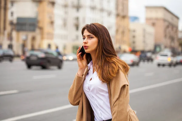 秋の通りに携帯電話を持つ若い美しい女の子 — ストック写真