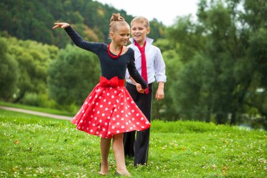 Çocuklar dans ediyor. Takım elbiseli çift, yazın açık havada.