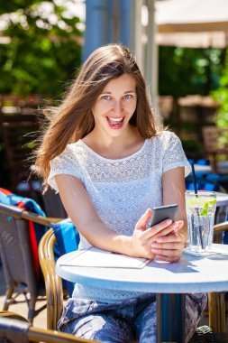 Sokakta bir kafede oturan soğuk bir içecekle güzel esmer bir kadın.