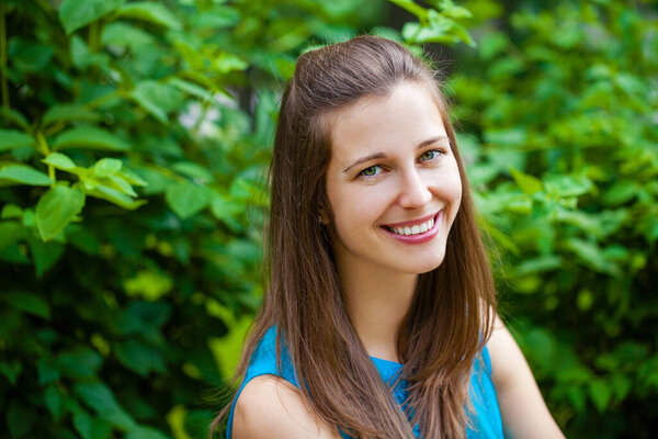 Close up portrait of beautiful young happy brunette woman with fresh and clean skin, summer street outdoors