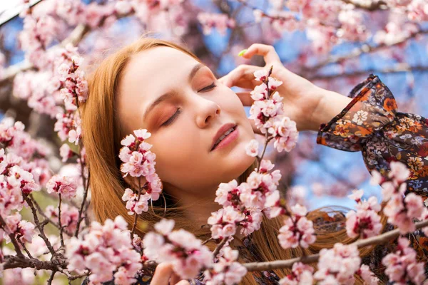 美丽的少女在樱桃树旁摆弄着粉红色的花朵 — 图库照片