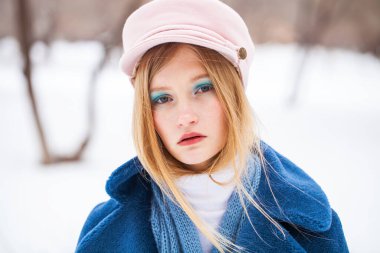 Güzellik uydur. Mavi paltolu ve pembe şapkalı güzel sarışın bir kızın portresi.