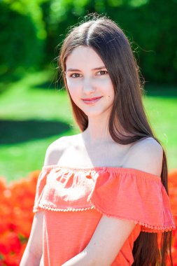 Kırmızı lalelerin arkasında poz veren güzel bir kızın portresi.