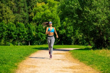 Atletik, mutlu, esmer bir kadın. Bir dizi fotoğraftan çayırda çalışıyor.