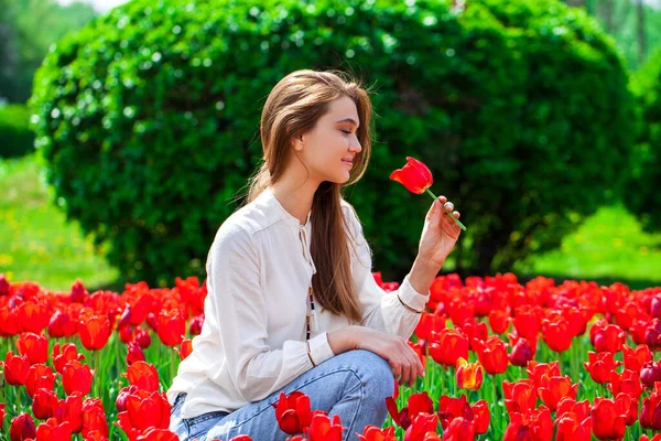 一个穿着夏装 穿着红色郁金香的年轻漂亮姑娘站在草坪上的画像 — 图库照片
