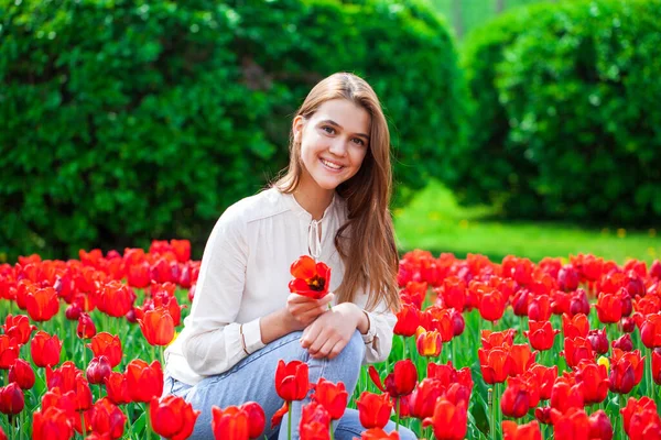 若いです美しいです女の子の肖像夏のドレスで芝生の上でポーズとともに赤いチューリップ — ストック写真