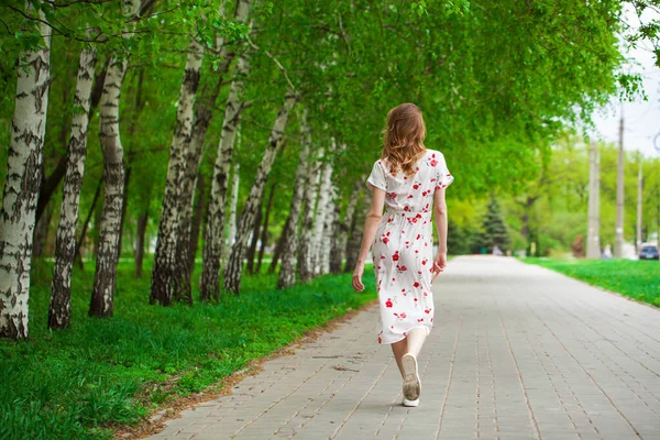 一个身穿白花裙的金发年轻女子的全身像 走在春天的大街上 — 图库照片