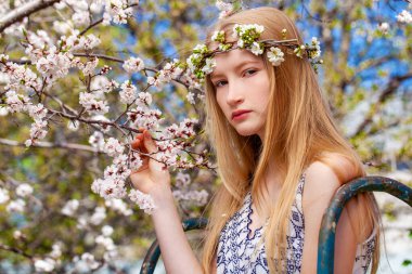 Bahar parkında poz veren genç sarışın bir kadının yakın portresi.