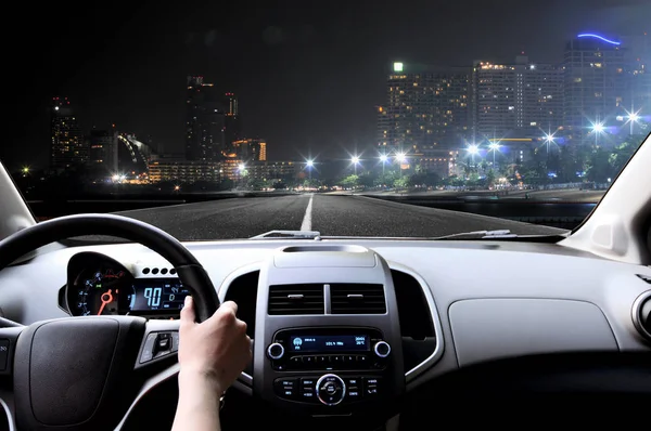 Чоловік водить машину через нічне місто — стокове фото