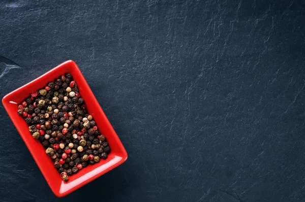 Pepparkorn i en röd skål — Stockfoto