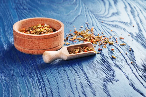 Koyu mavi zemin üzerine kaşıkla ahşap kase farklı kuru baharat