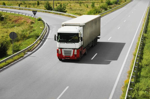 Kırsal yolu üzerinde gri römork ile beyaz ve kırmızı kamyon