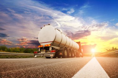 Gökyüzü günbatımı ile kırsal yolda yakıt nakliye büyük metal tanker kamyon arka görünümü