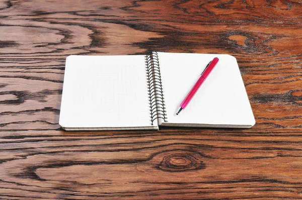 School notebook and pink pen on the brown wooden background