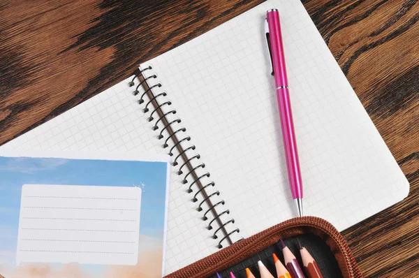 铅笔盒里满是彩色铅笔 学校抄写本和钢笔在棕色的木桌上 — 图库照片