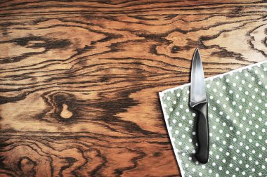 Koyu ahşap arka plan ile noktalı peçete üzerinde büyük siyah bıçak
