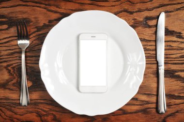 boş ekran gümüş bıçak ile plaka üzerinde ve ahşap zemin üzerine çatal ile Smartphone