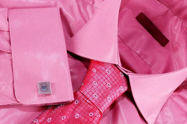 Close-up of a pink shirt with tie, cufflink and dark red brand label