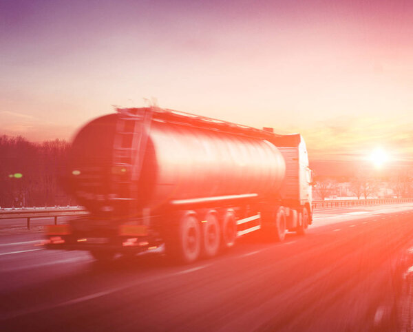 Truck with fuel on winter highway at sunset