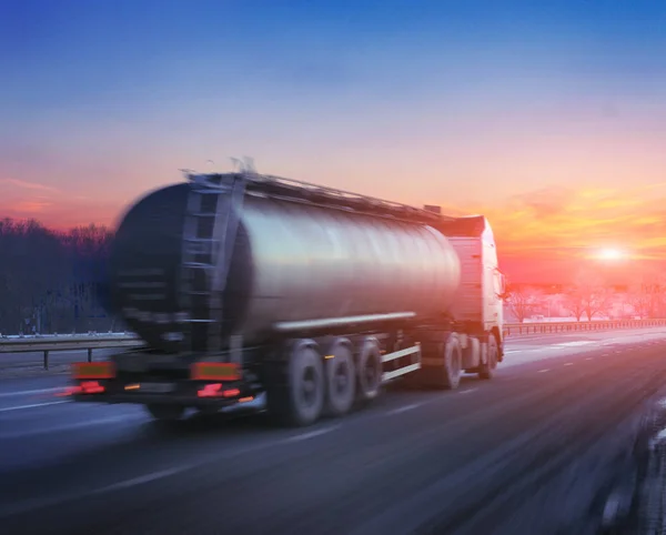 Truck with the fuel on winter highway at sunset