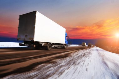 Beyaz kutu kar gece gökyüzü günbatımı ile karşı ile kırsal kış yolda hızlı kamyon sürüş