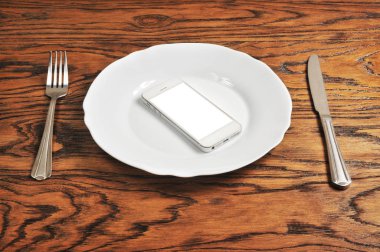 boş ekran gümüş bıçak ile plaka üzerinde ve çatal ahşap arka plan üzerinde beyaz smartphone