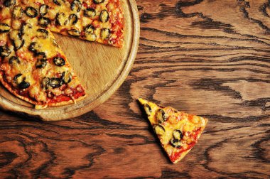 Güzel pizza bir dilim yuvarlak tahta üzerinde koyu ahşap bir masa üzerinde