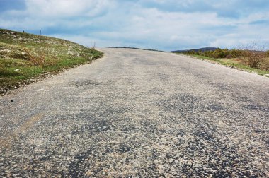 Beyaz bulutlu gökyüzü ile mavi gökyüzüne karşı çimen ve orman ile boş kırsal yol