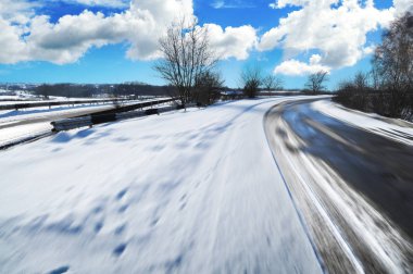 Boş kış kırsal yol hareket ağaçlar ve mavi gökyüzü bulutlu karşı beyaz kar