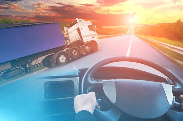 Abstract background with truck with trailer, truck steering wheel and road against sky with orange and blue lights