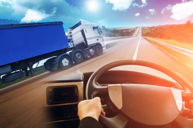 Abstract background with truck with trailer, truck steering wheel and road against sky with blue and orange lights