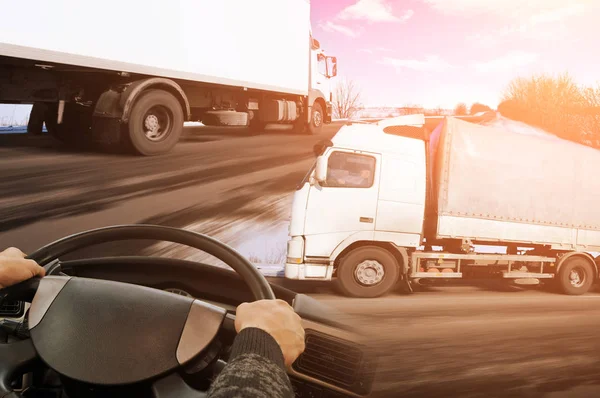 Abstract background with truck steering wheel and two big trucks against blue sky with clouds and orange light