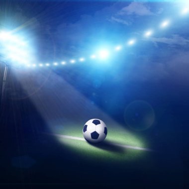 Futbol sahasının ortasında siyah beyaz top yeşil çimlerde ve stadyum lambasında duruyor.