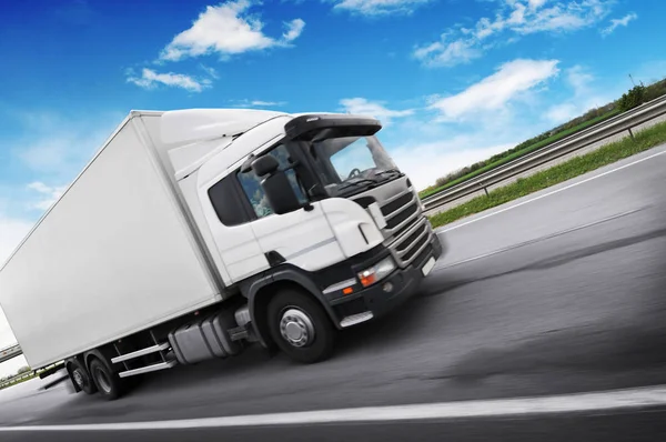 A truck driving fast on the countryside road with trees and bush Royalty Free Stock Photos