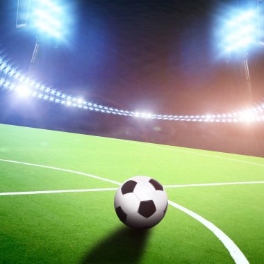 Green football field with ball on stadium with bright light and flashes at night
