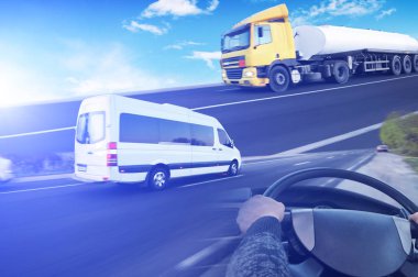 Beyaz minibüslü, direksiyonlu ve mavi ışıklı büyük tankerli soyut bir arka plan.